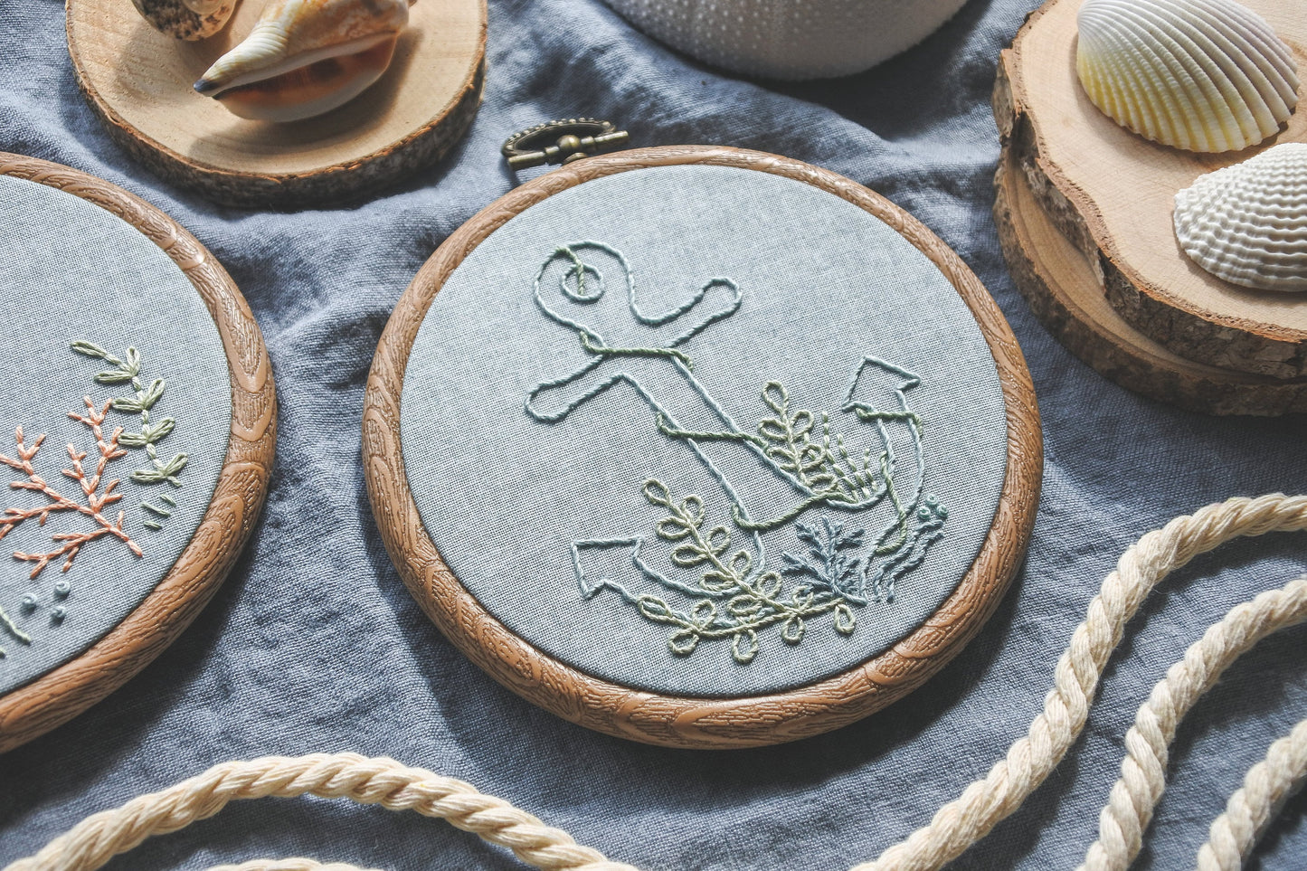 Angled view of underwater anchor embroidery hoop stitched on light blue fabric