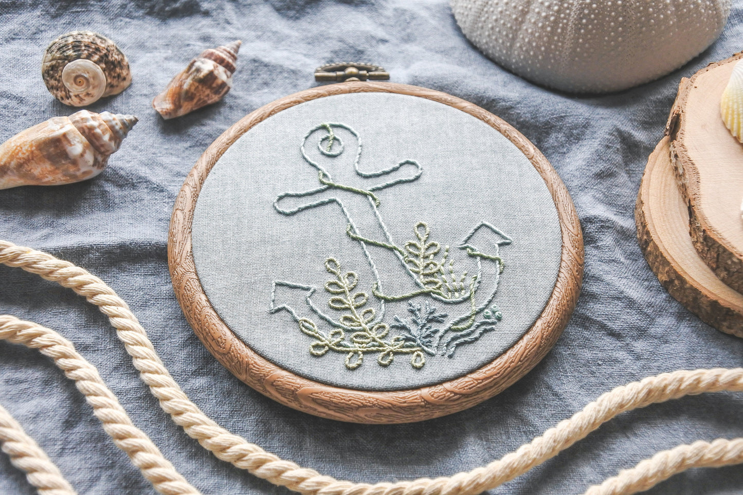 Angled photo of the anchor embroidery hoop showing stitched seaweed, coral and ocean details