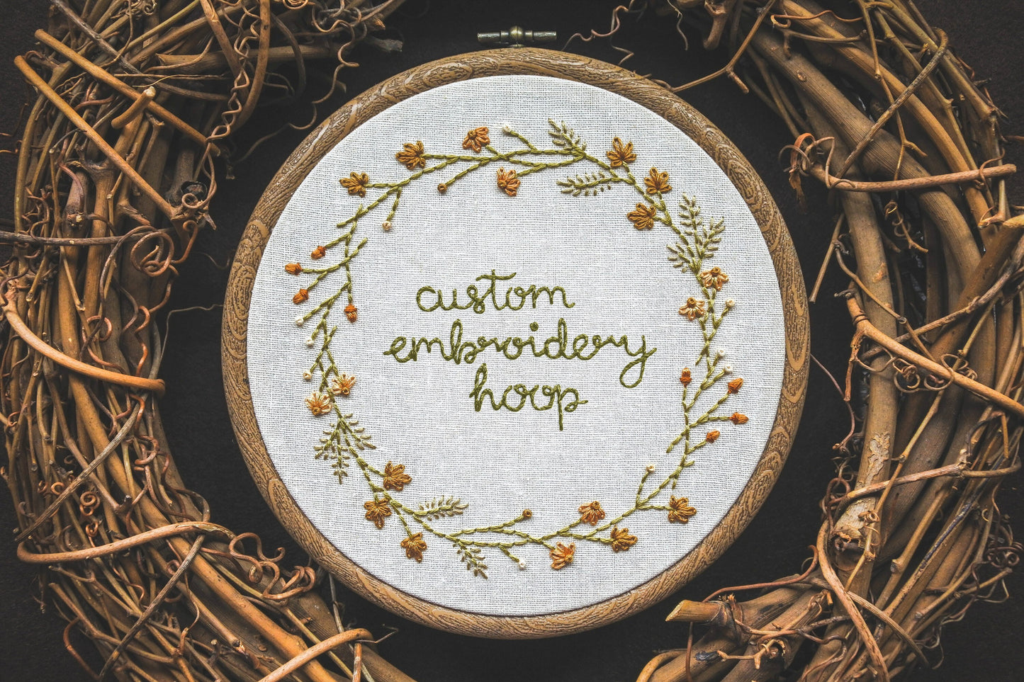 Custom autumn wreath embroidery hoop with hand-stitched leaves, grasses, coneflowers, acorns, and embroidered lettering in green thread