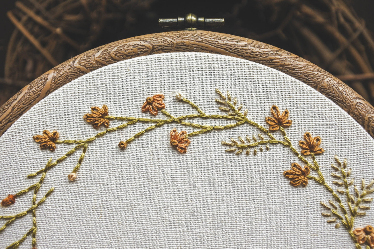 Closeup of details in the autumn wreath design, showing grasses, coneflowers and leaves in warm muted autumnal colours