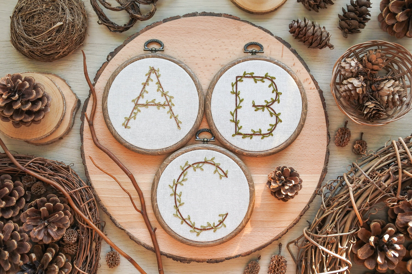 Flatlay of 4-inch hand embroidered A, B, and C hoops with leafy vine designs