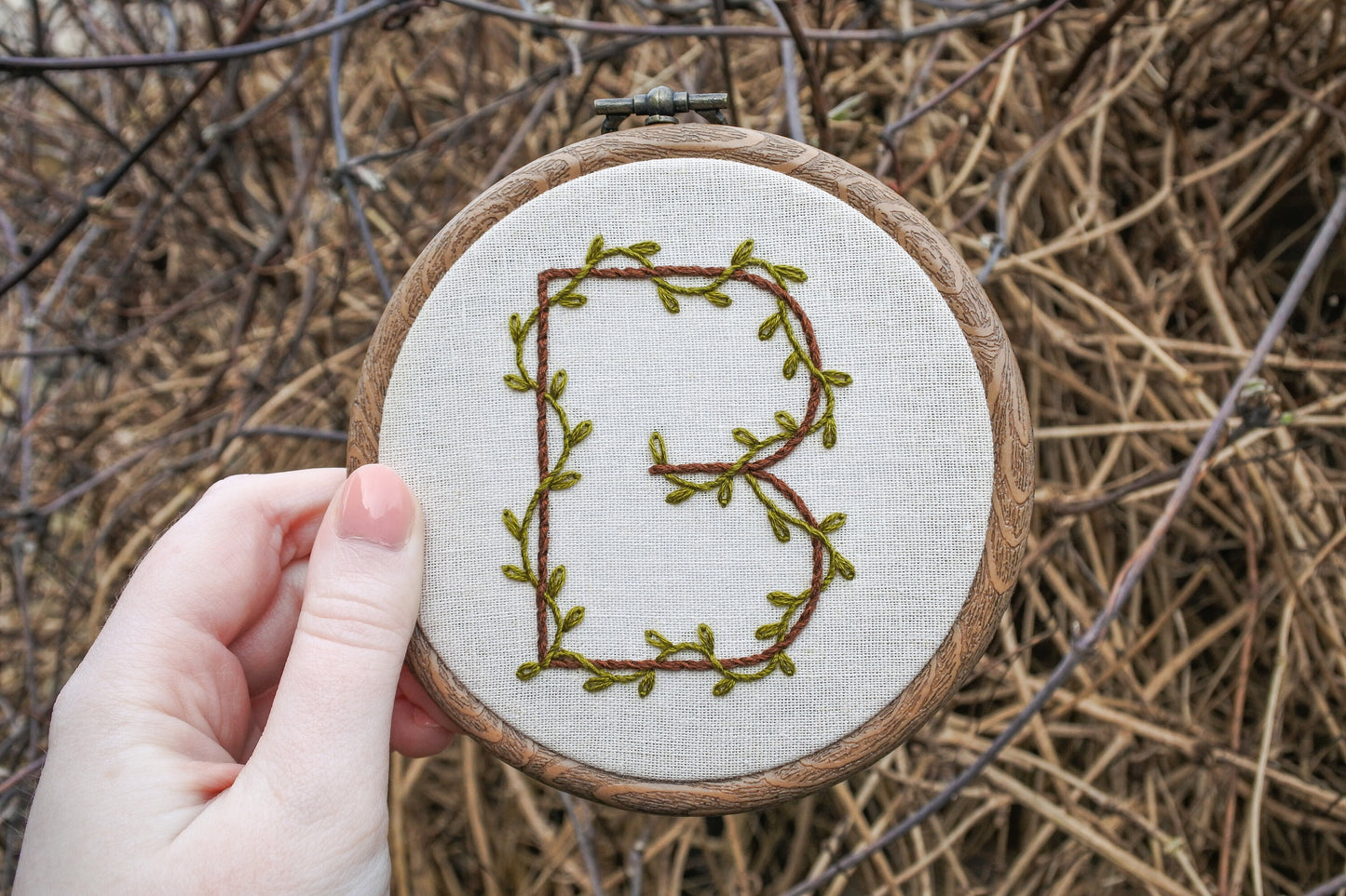 hand holding letter b botanical embroidery hoop outside