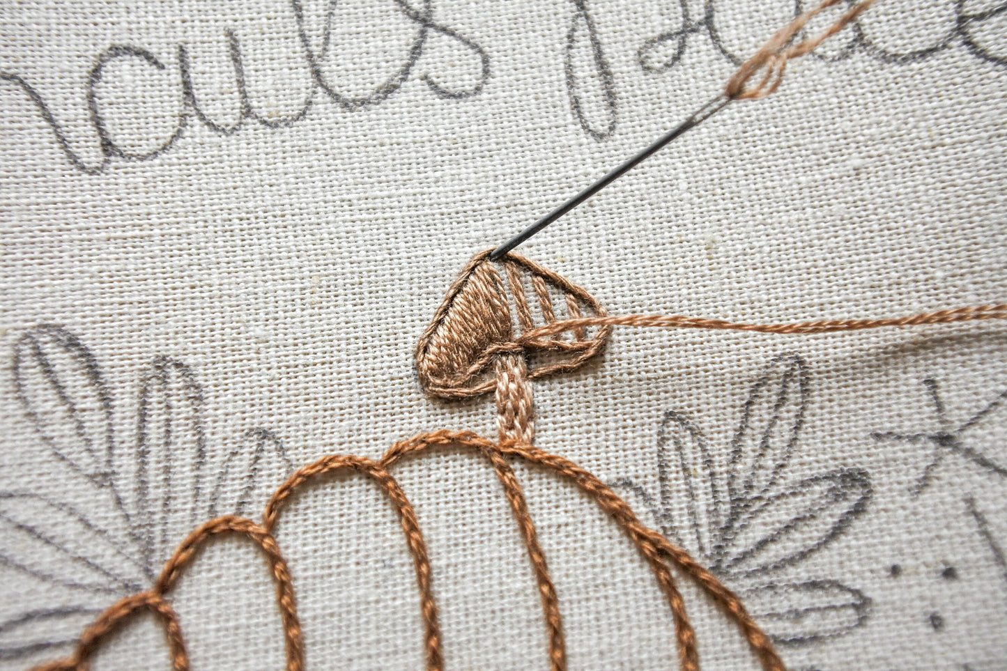Needle and thread stitching a small brown mushroom