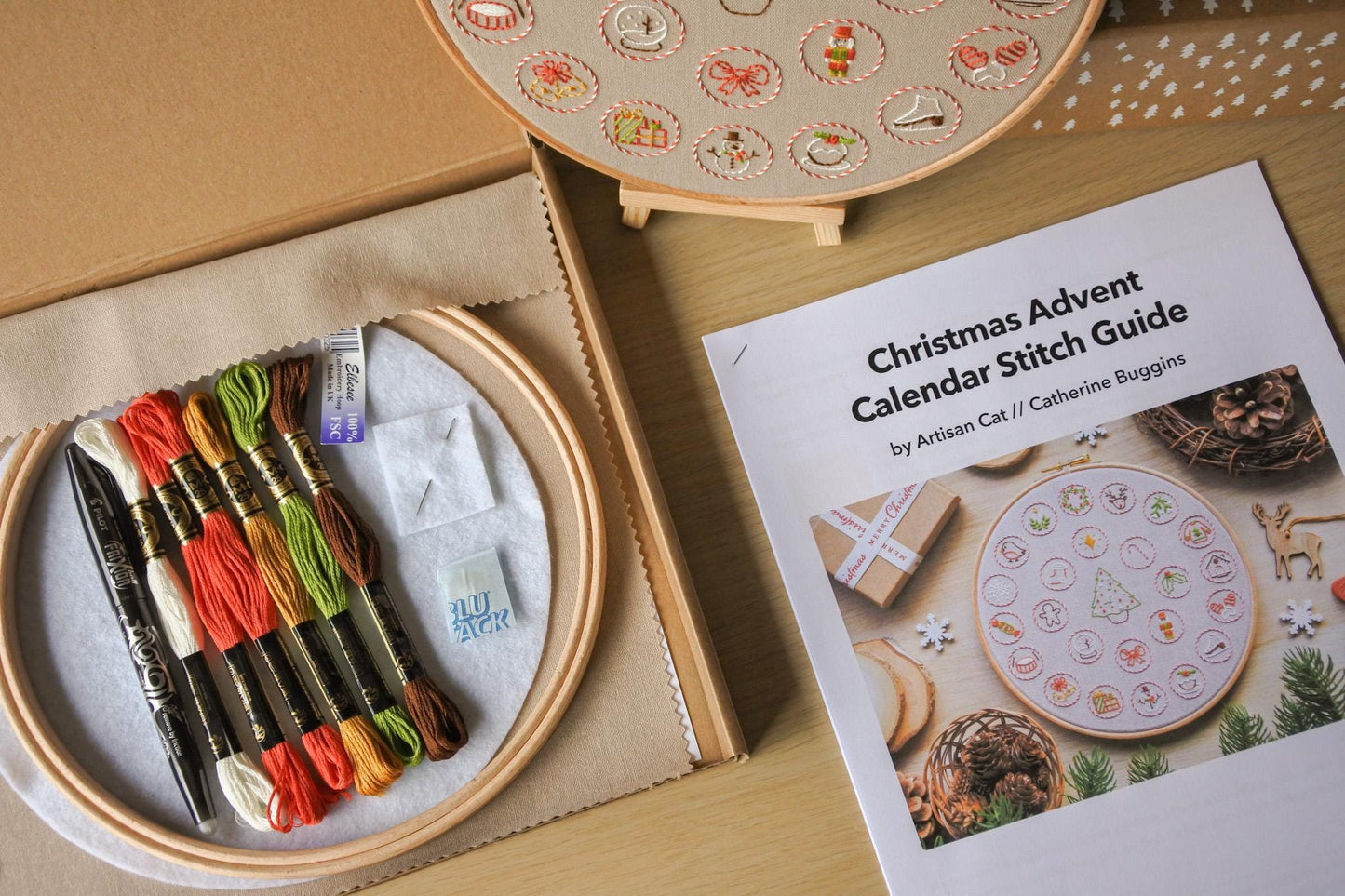 Close-up of the Christmas advent calendar kit box and printed stitch guide, showcasing the contents for a festive embroidery project.