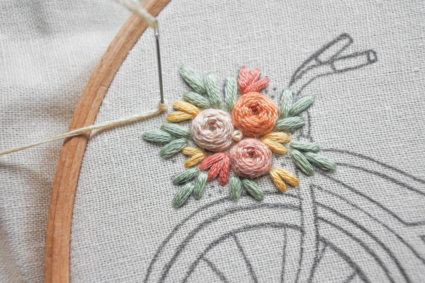 Close-up of a French knot in progress on one of the floral bouquets in the floral bicycle embroidery design.