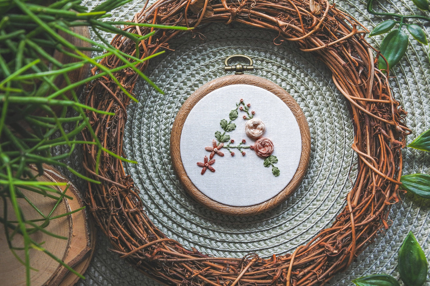 Hand-embroidered floral letter A hoop with peach flowers and green foliage in a 3-inch wood-effect hoop.