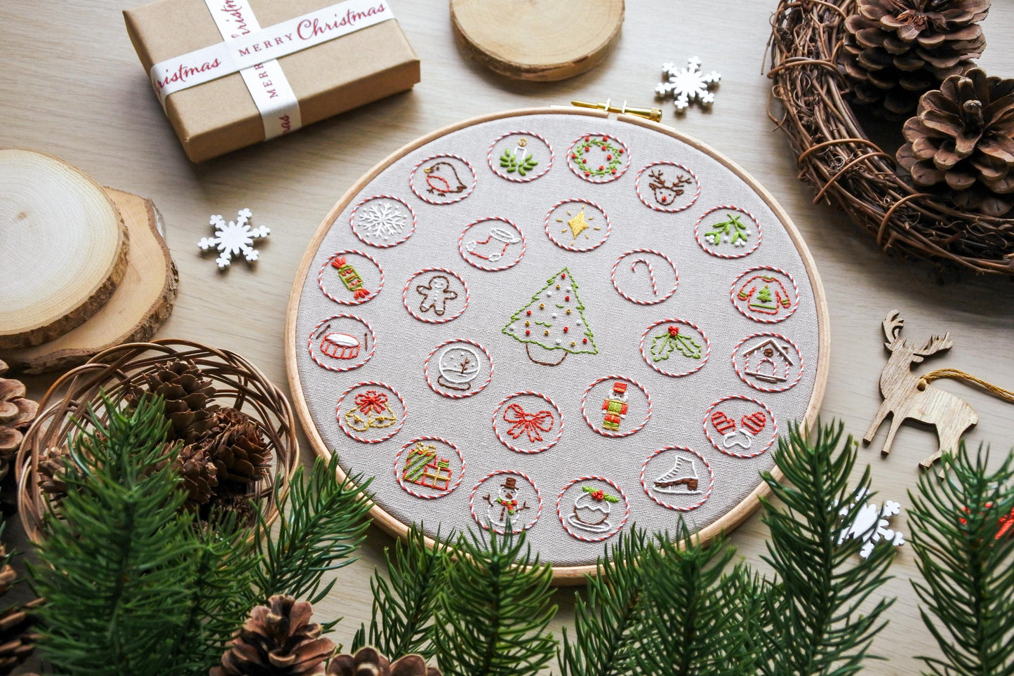 Flat lay of finished hand embroidered Christmas advent calendar hoop, featuring festive mini designs around a Christmas tree.