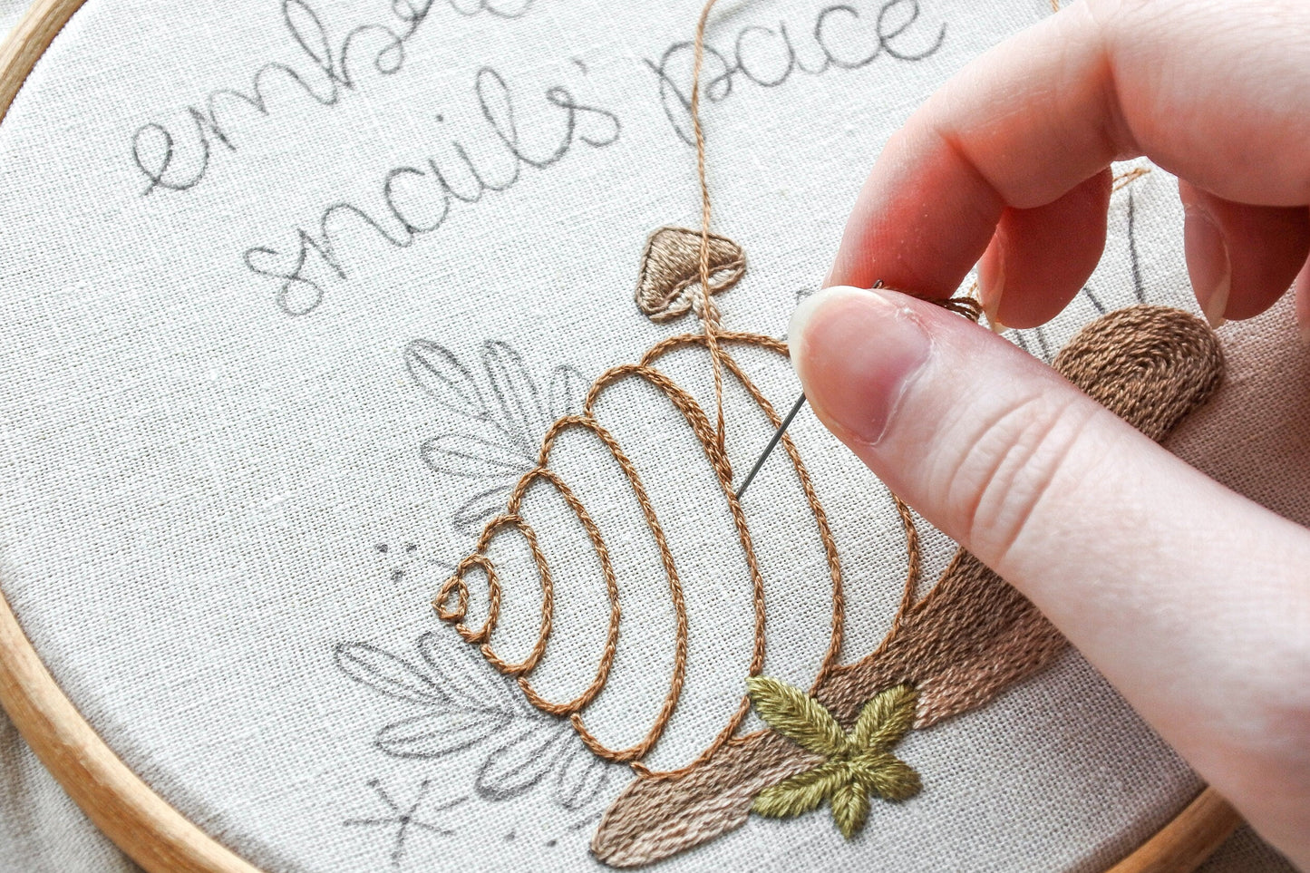 Progress shot of hand holding a needle stitching the snail's shell