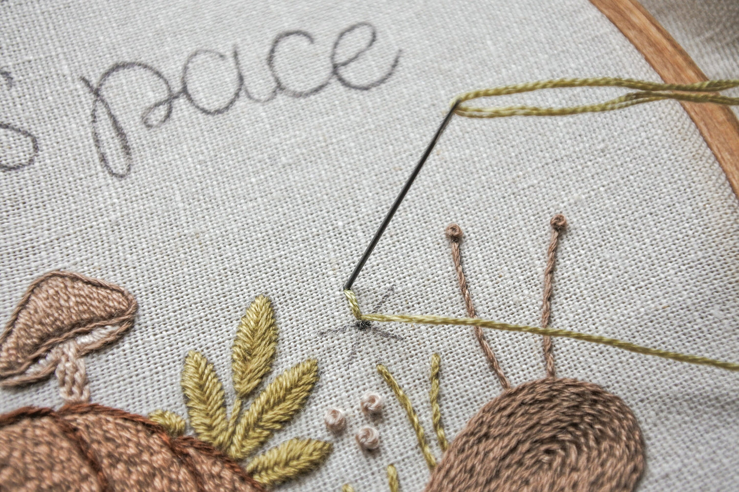 Progress shot of needle and thread stitching a flower