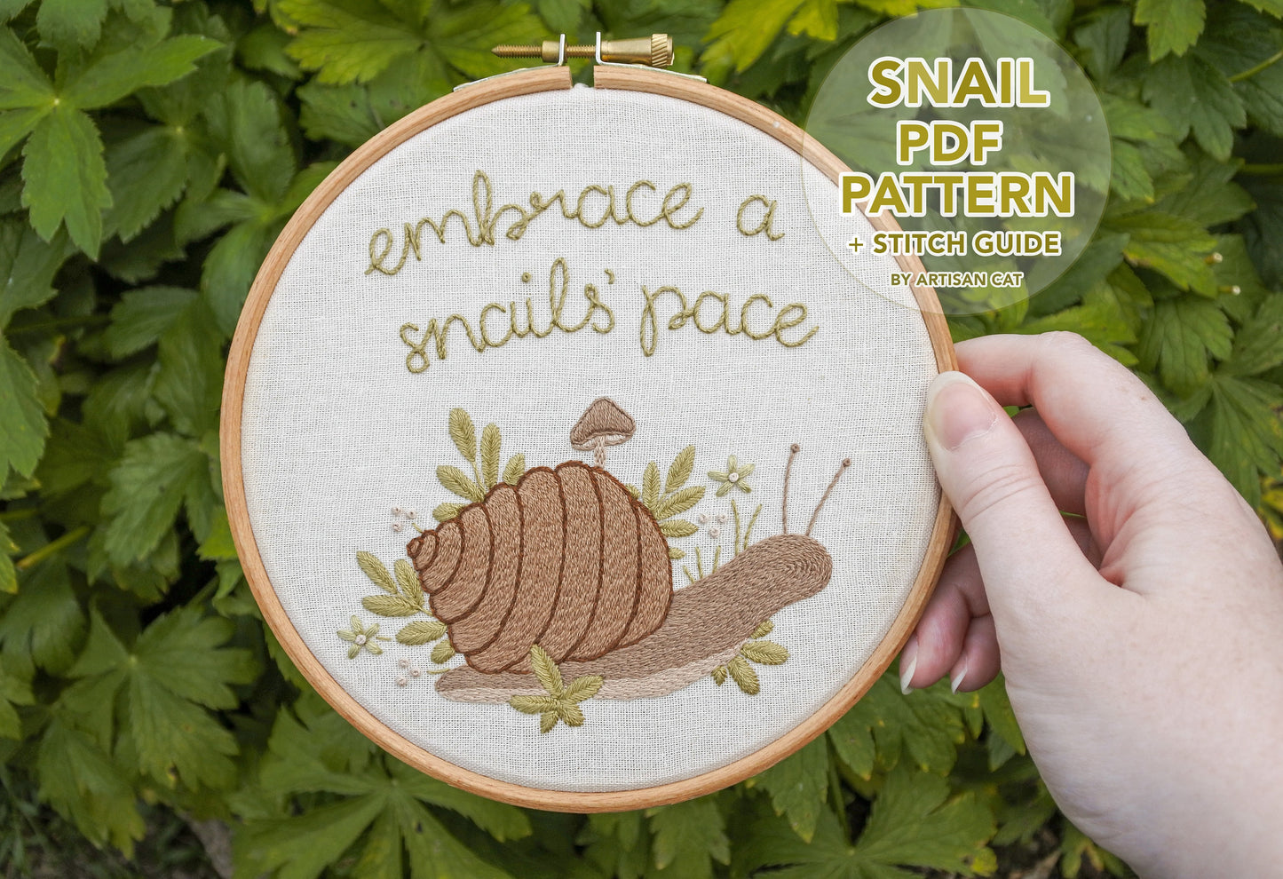 Hand holding the snail embroidery hoop with text overlay in a bubble saying 'Snail PDF Pattern and Stitch Guide by Artisan Cat'