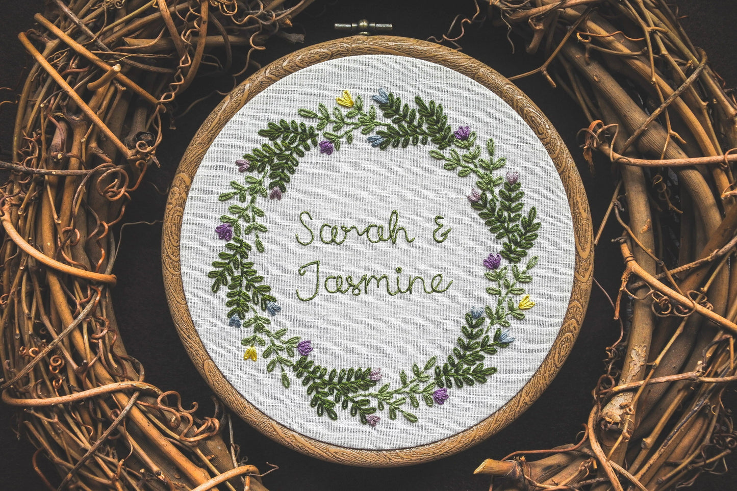 Spring wreath embroidery hoop with the names 'Sarah and Jasmine' in the centre, surrounded by embroidered flowers and foliage.