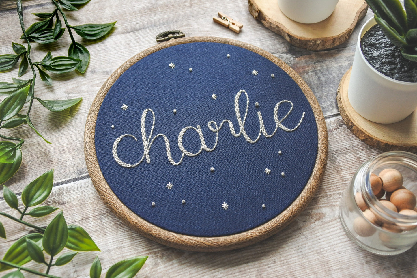 Navy blue hand embroidered hoop with the name Charlie stitched in white thread, surrounded by stars