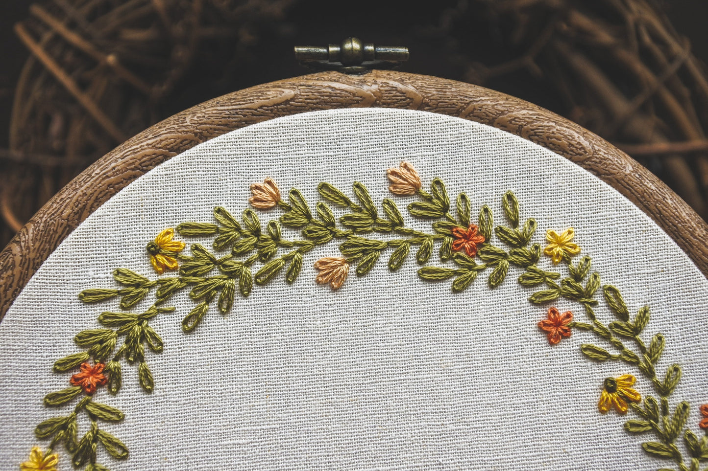 Detail view of the hand stitched name Bella framed by vibrant summer flowers and foliage