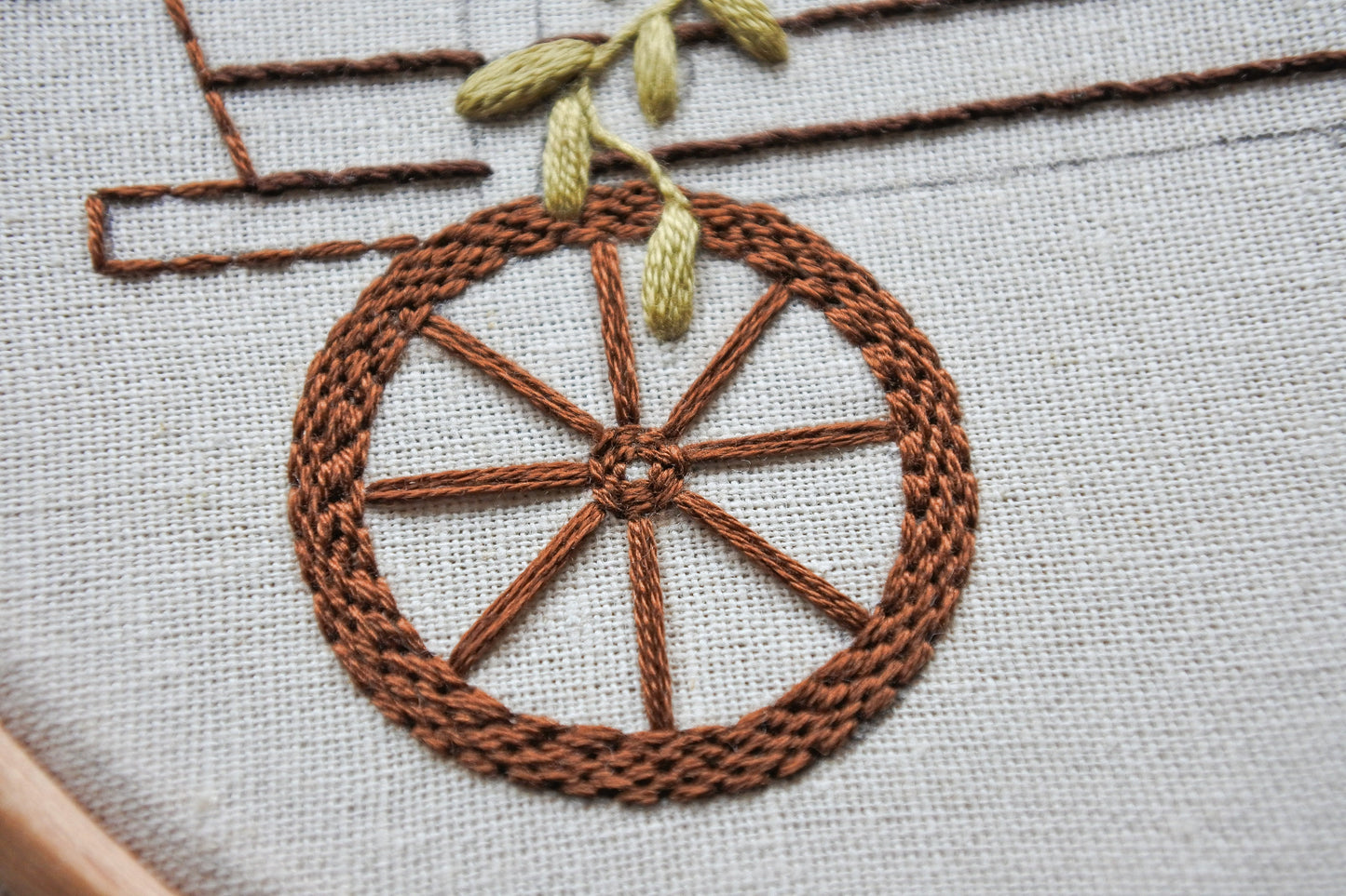 Closeup of wagon wheel embroidery details from the autumn floral embroidery pattern
