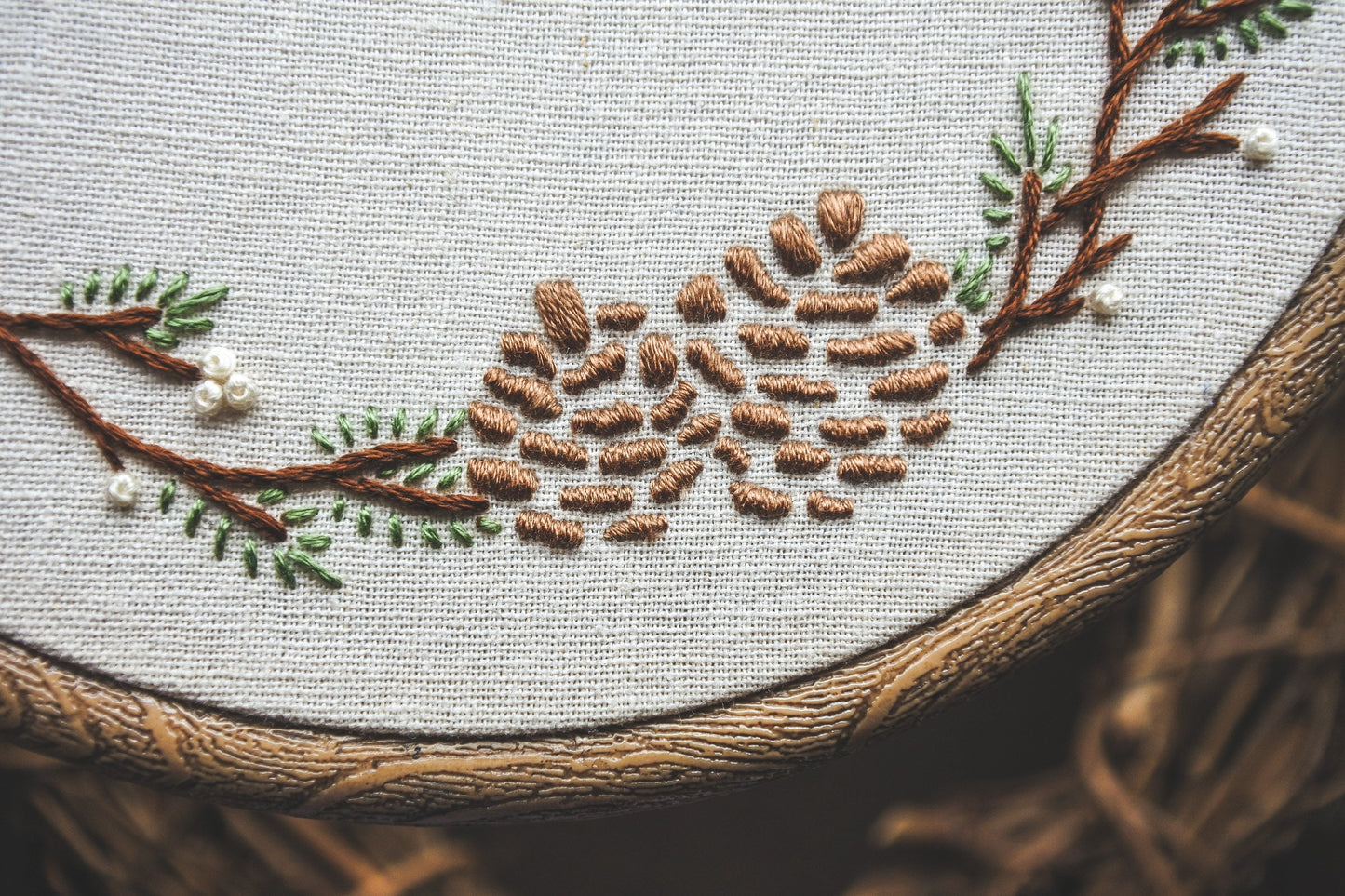 Closeup of pinecones pine branches stitched in a winter embroidery design
