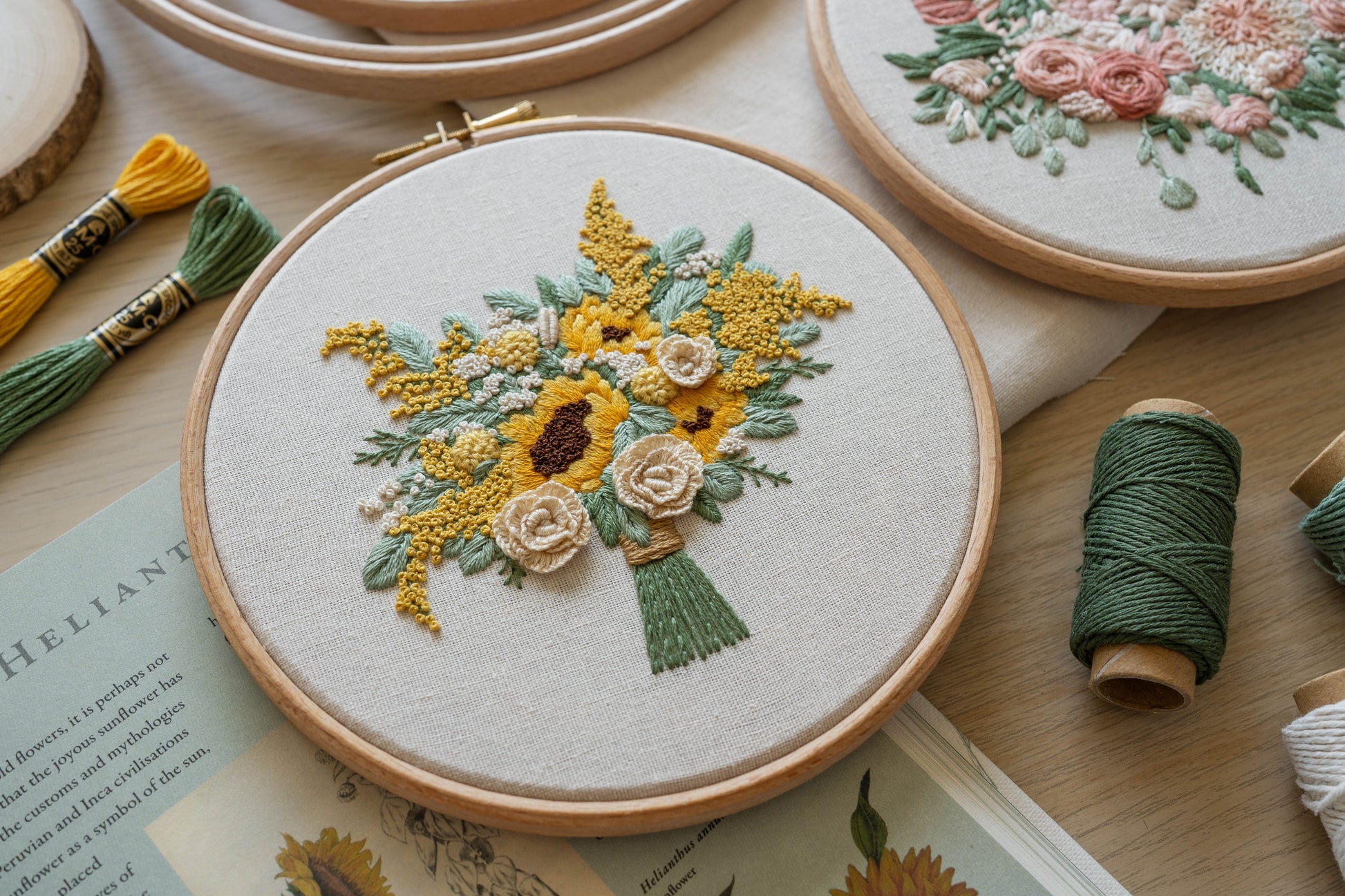 Angled close-up of hand-embroidered sunflower and rose bouquet hoop, showcasing 3D textured rose petals and detailed stitching