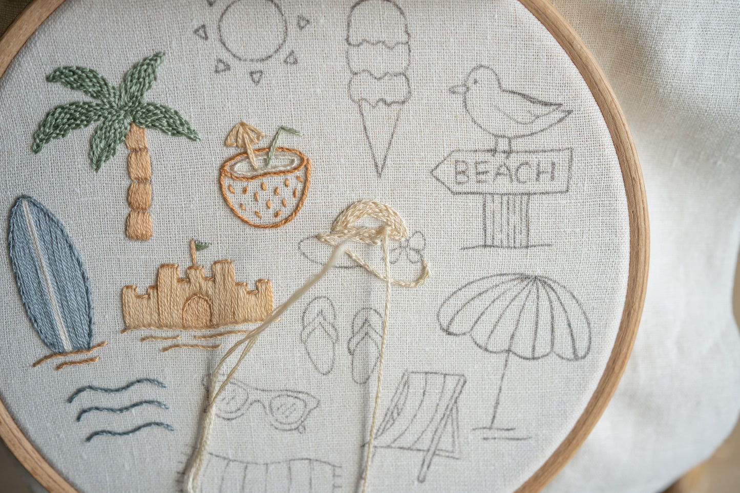 Embroidery hoop with beach-themed designs including palm trees, ice cream, and sun.