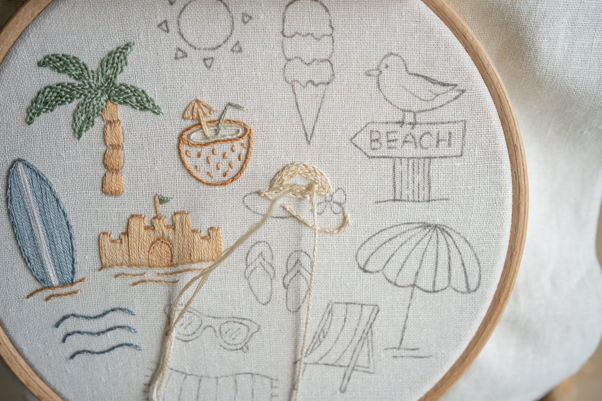 Embroidery hoop with beach-themed designs including palm trees, ice cream, and sun.