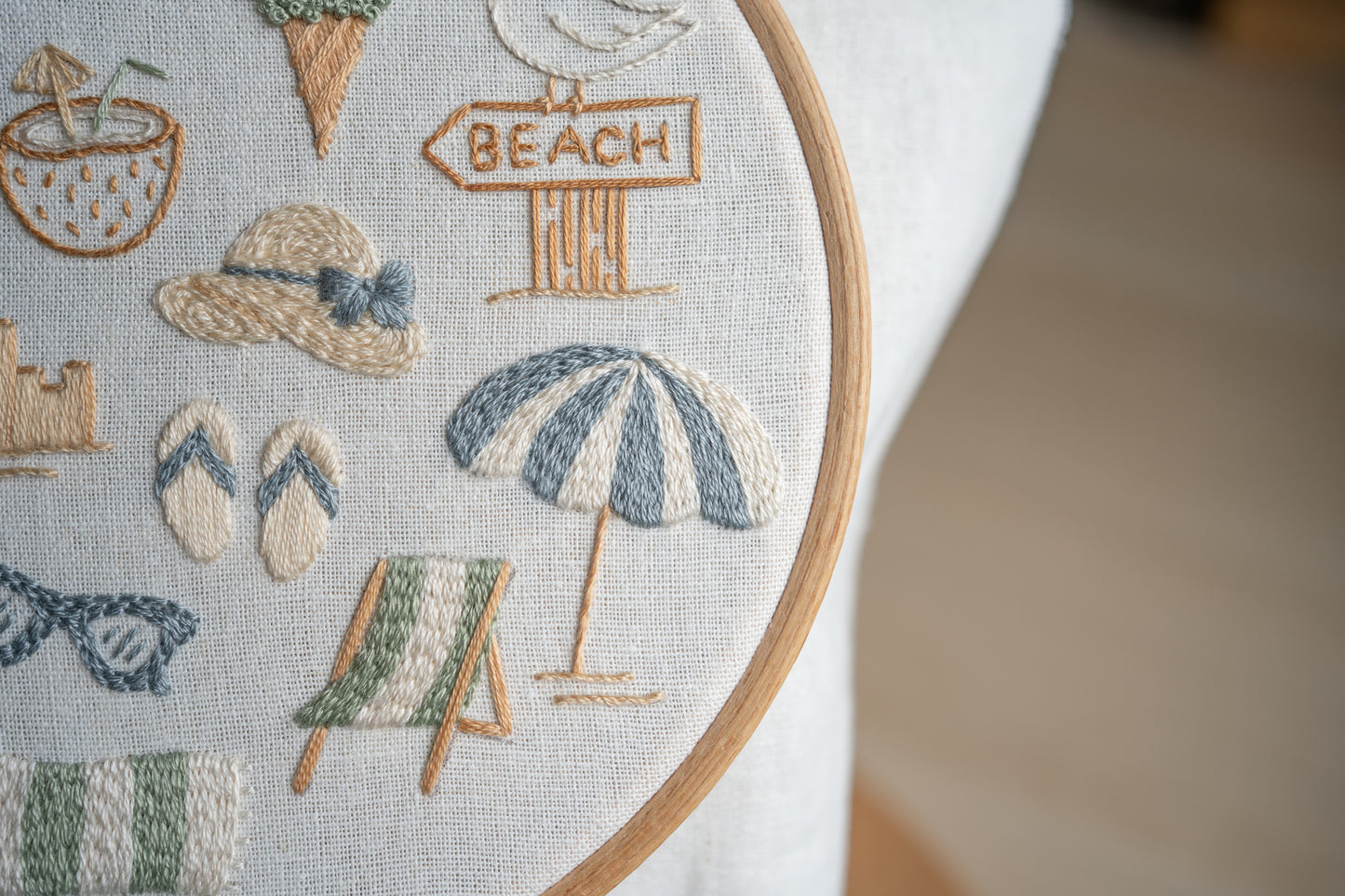 Embroidery hoop with beach-themed designs including an umbrella, sandals, and a 'Beach' sign.