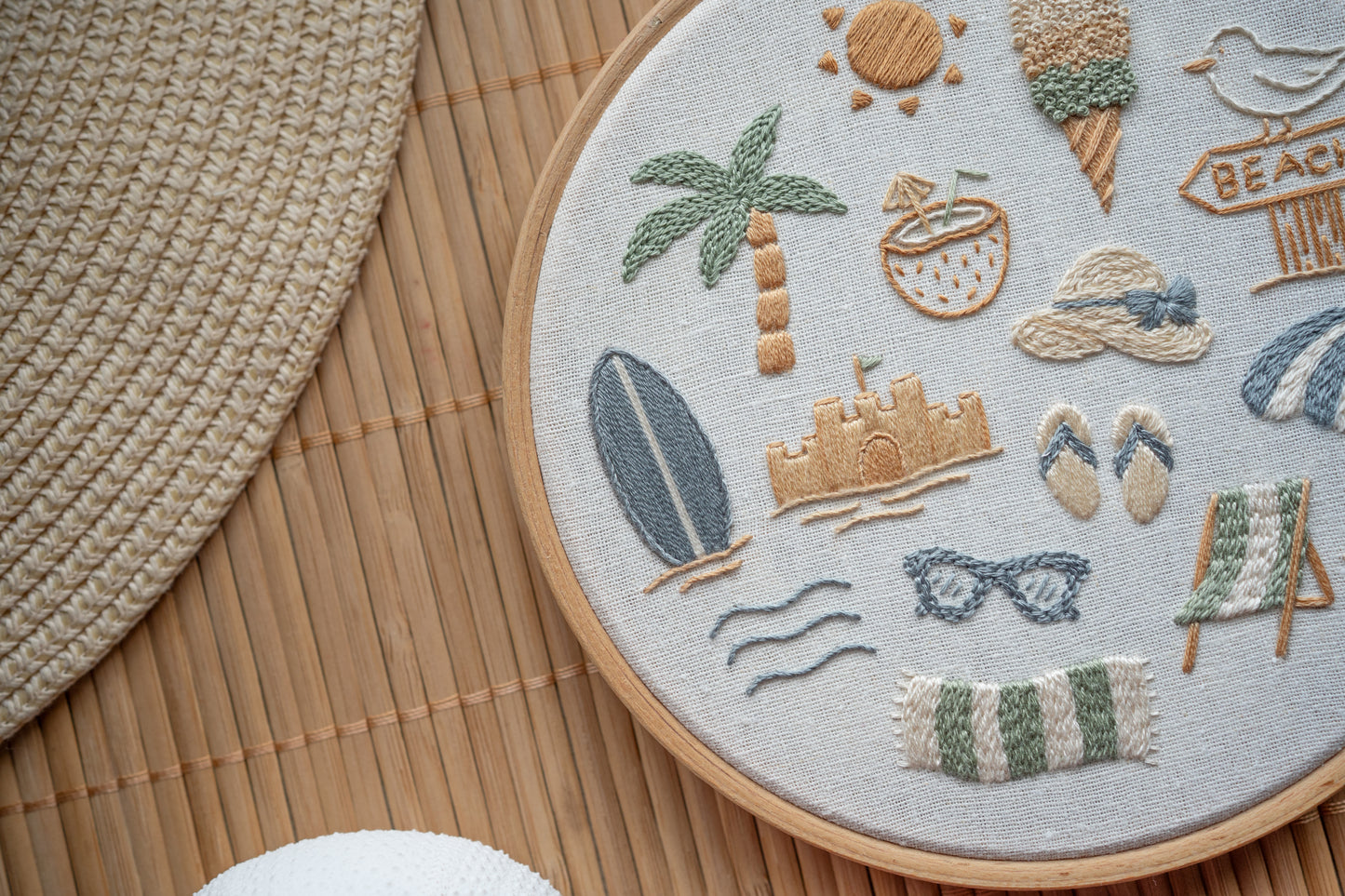 Embroidery hoop with beach-themed designs on a wooden surface