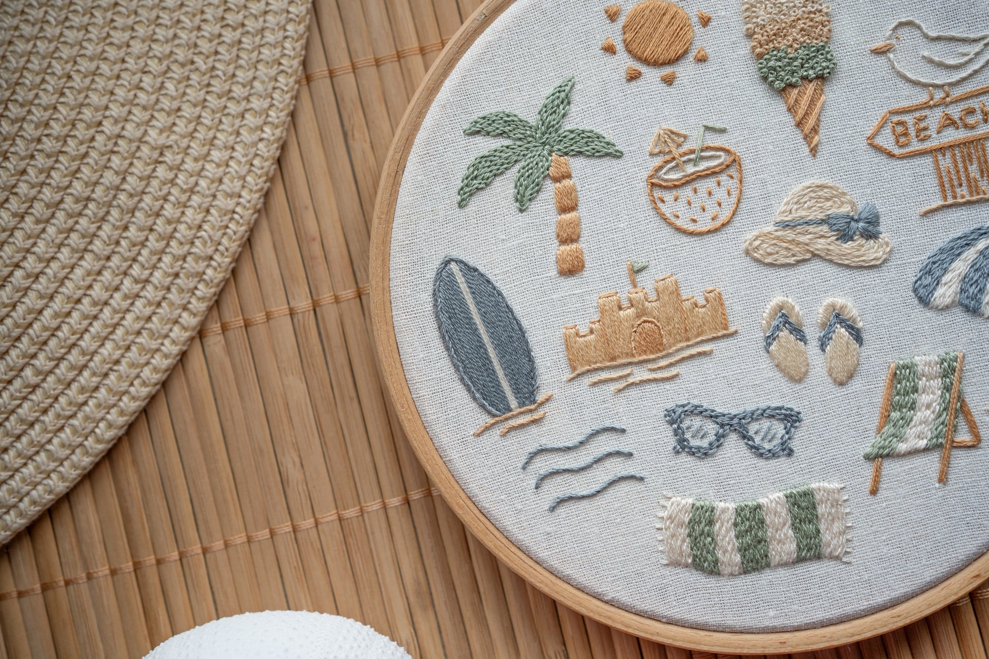 Embroidery hoop with beach-themed designs on a wooden surface