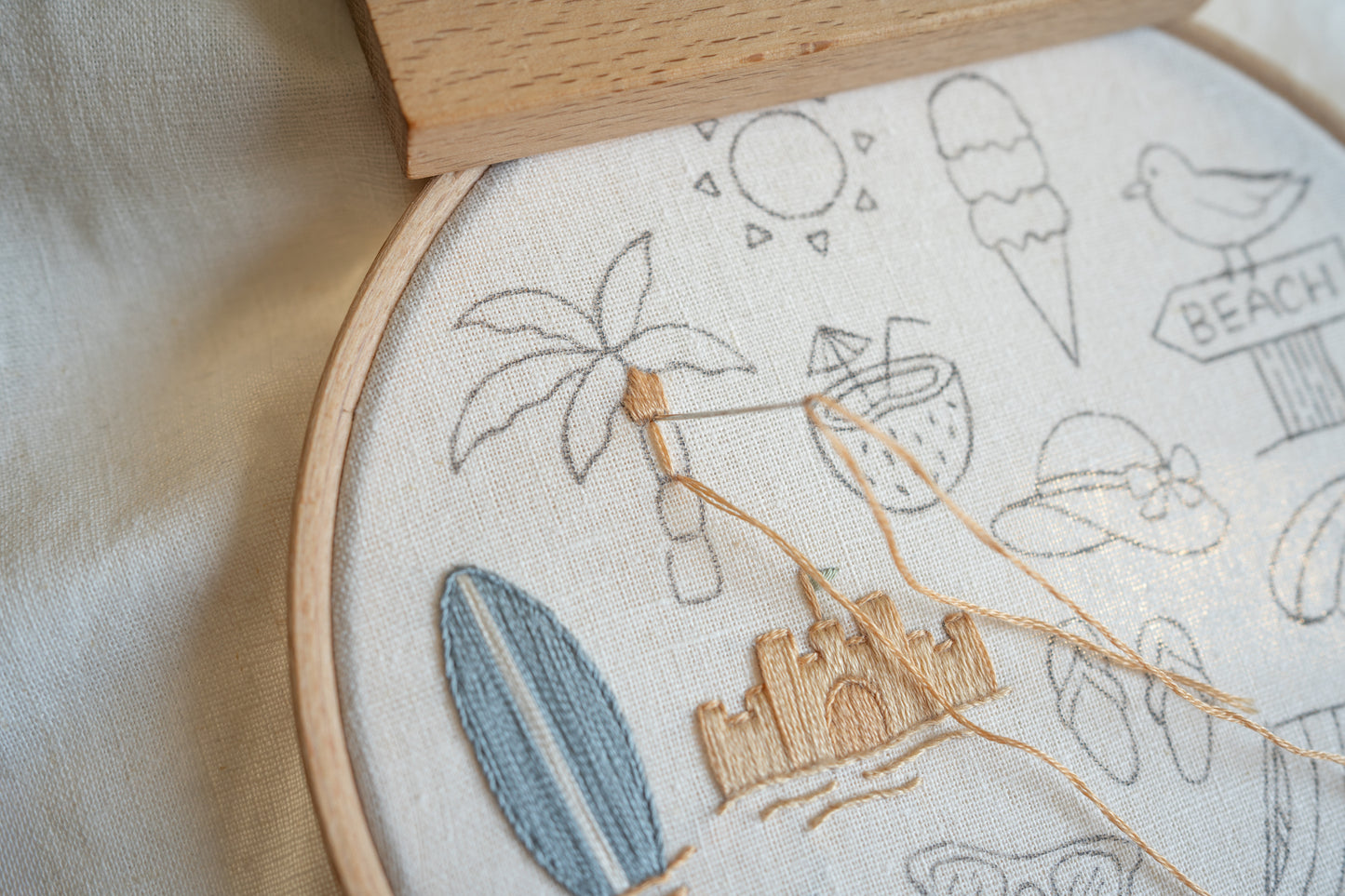 Embroidery hoop with beach-themed embroidery on a light fabric background