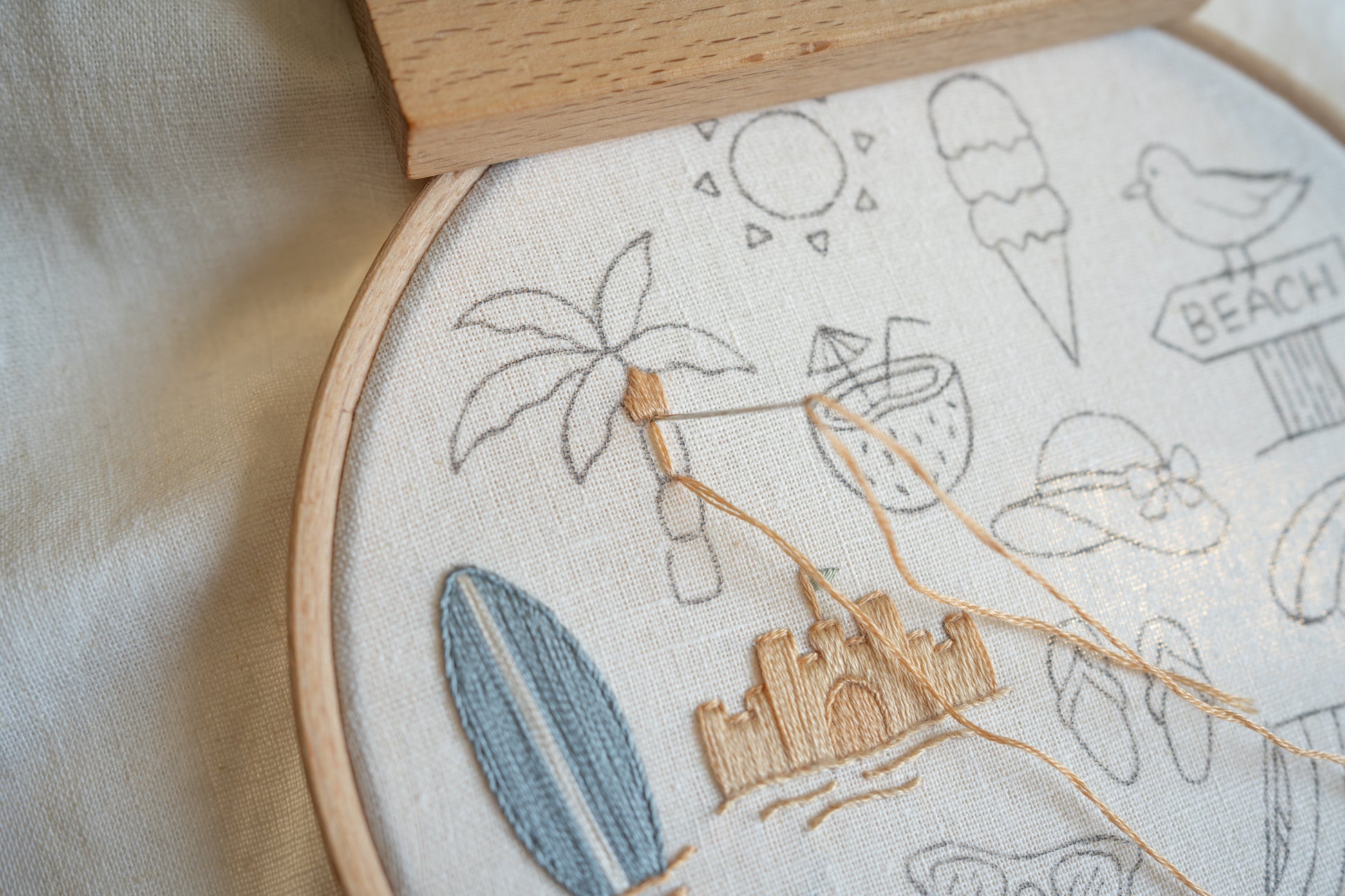 Embroidery hoop with beach-themed embroidery on a light fabric background