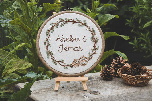 Abeba and Jemal hoop displayed outside on a mini wooden easel next to pinecones