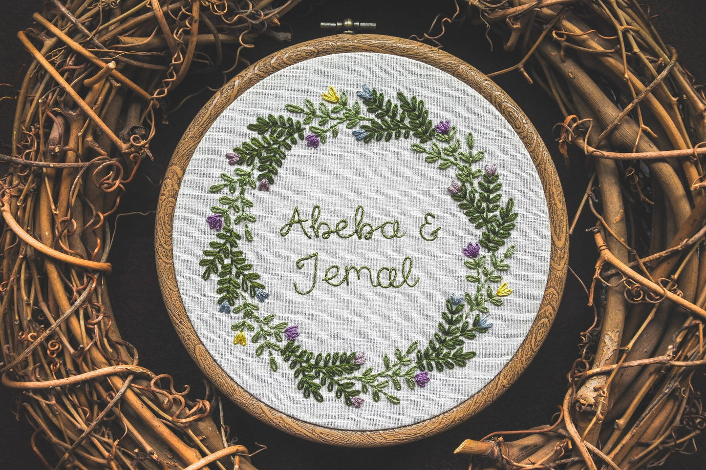 Personalised spring name hoop with Abeba and Jemal stitched in the centre of a floral wreath