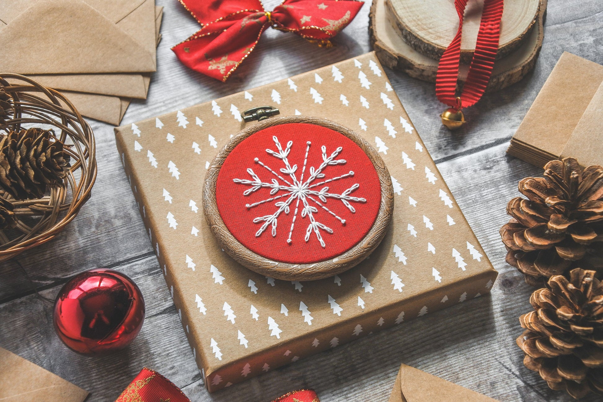 Angled view of white snowflake embroidery on red fabric in a 3-inch wood-effect hoop