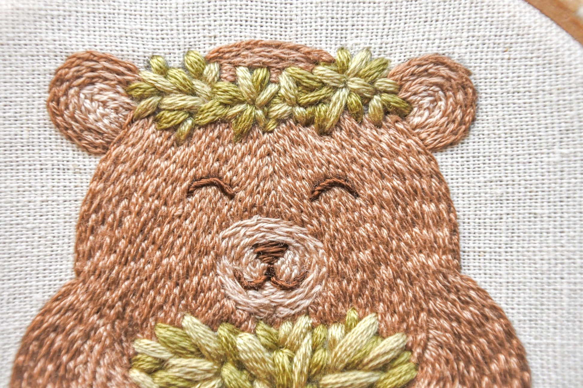 Close-up of the finished bear face, wearing a leaf garland crown in the embroidery design.