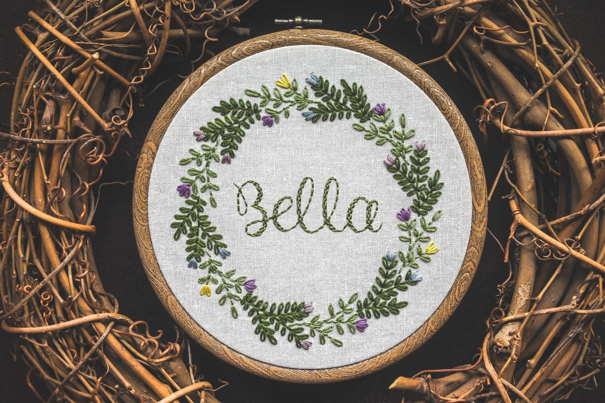 Embroidered name hoop with Bella stitched in the centre of a spring floral wreath