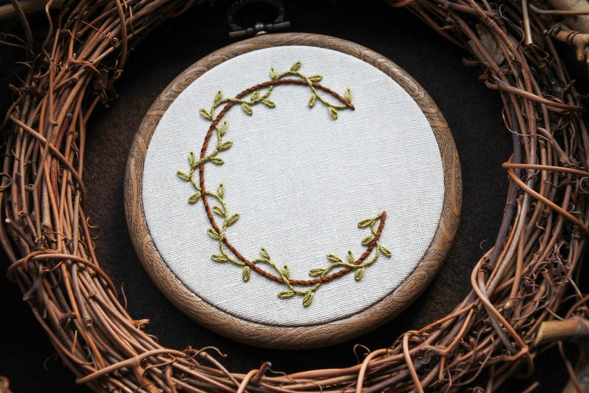 Botanical letter C embroidery hoop with green vines and brown stitched letter on neutral fabric
