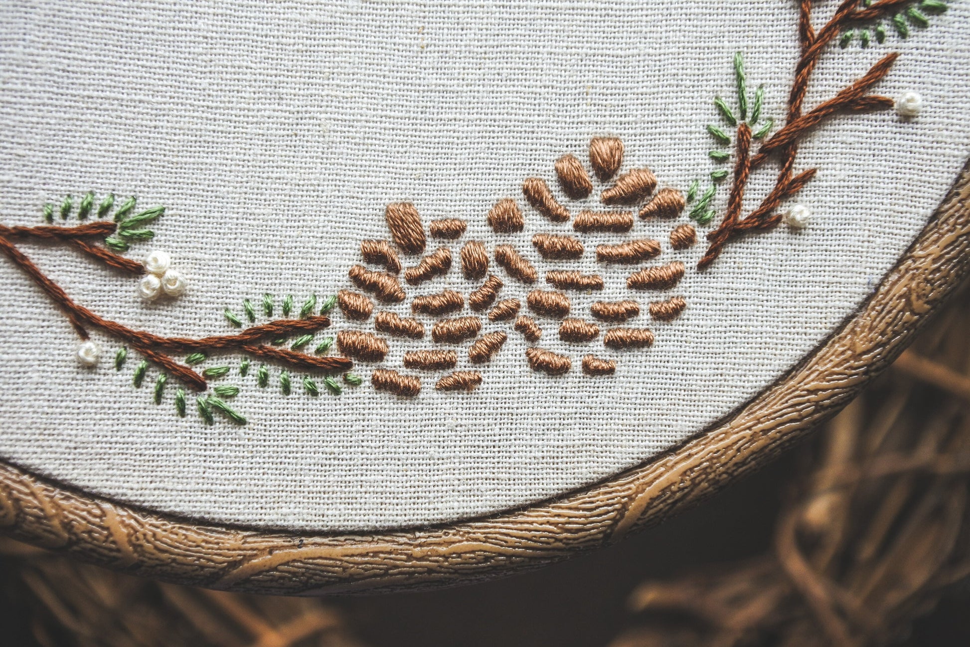 Closeup of pinecones embroidered on the winter wreath hoop