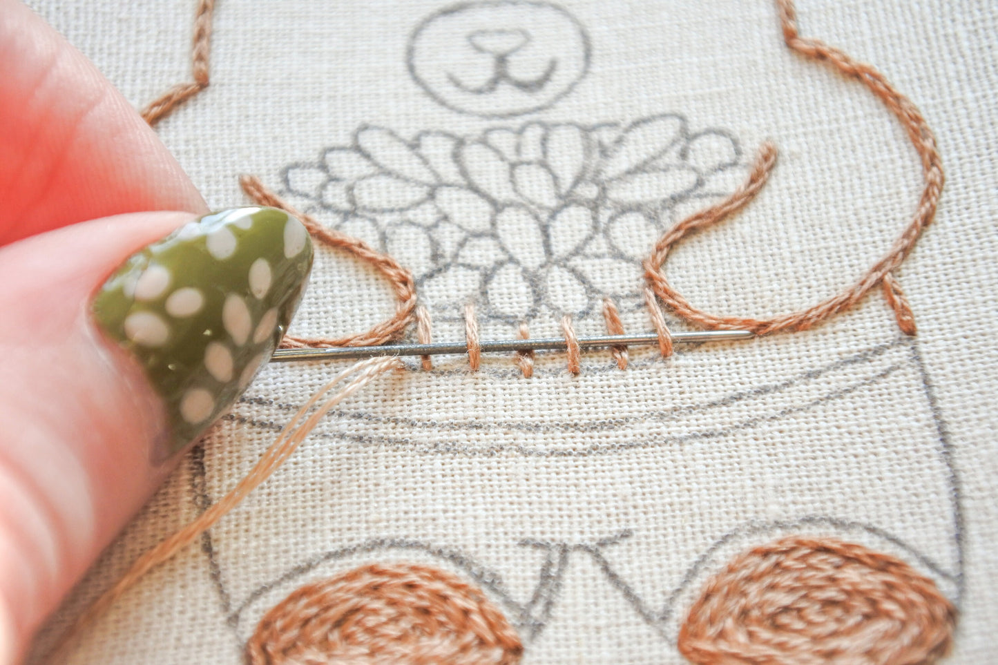 Close-up of stitching the woven basket in the bear embroidery design.