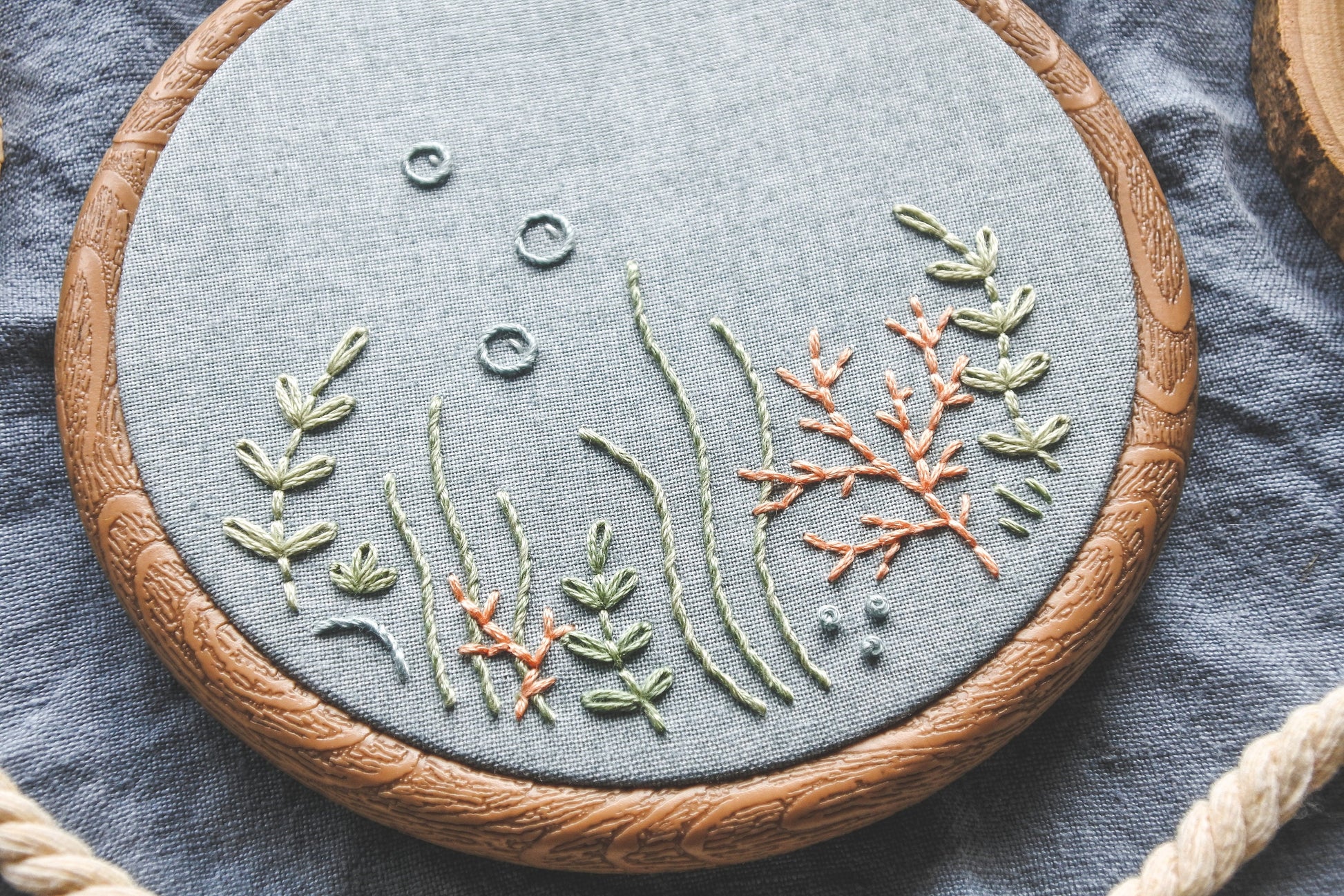 Closeup of coral reef embroidery design on light blue fabric