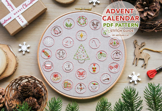 Flatlay of hand-embroidered Christmas advent calendar design with 'Advent Calendar PDF Pattern and Stitch Guide by Artisan Cat' text.