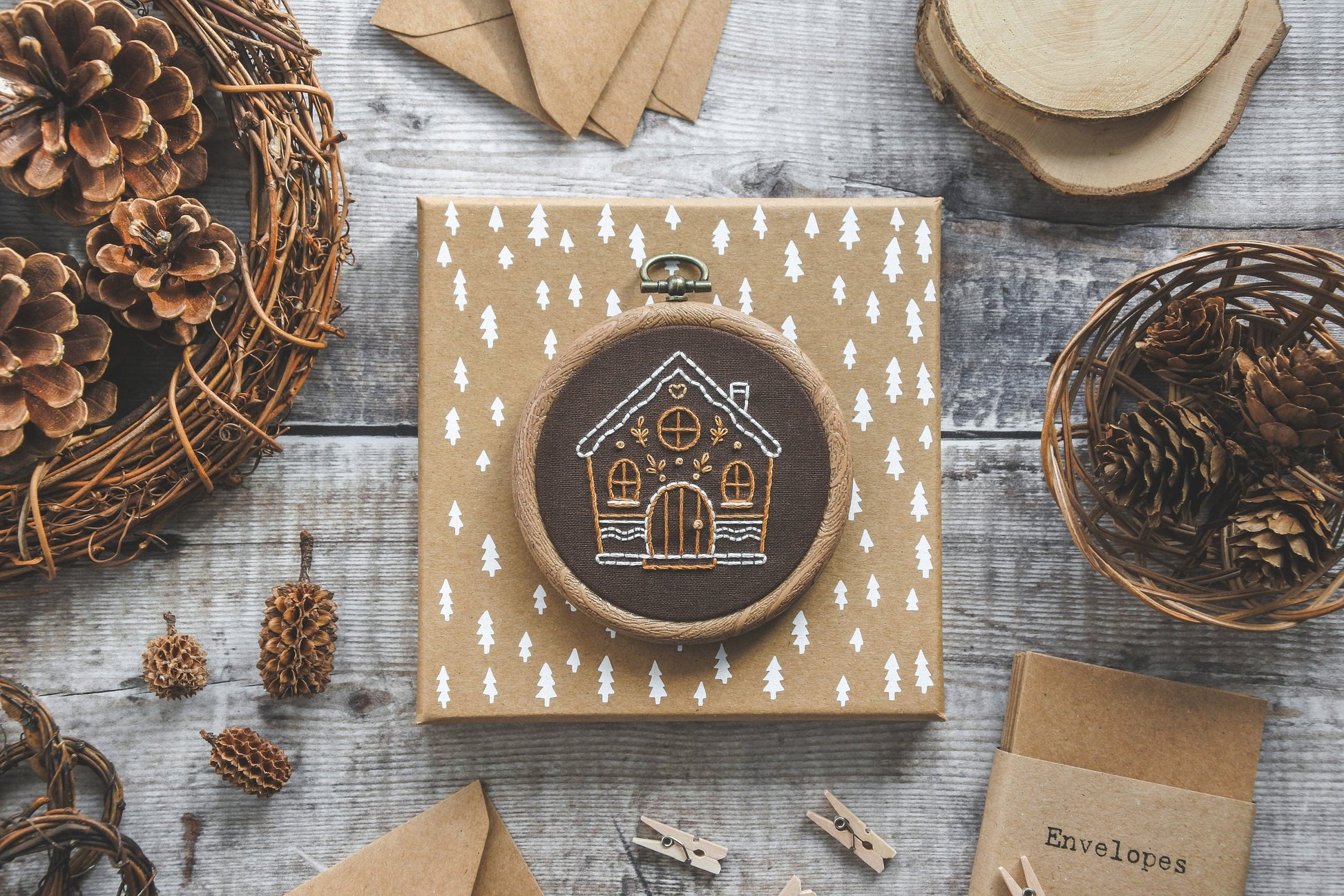 Flatlay of hand-embroidered gingerbread house design in hoop, showing the brown fabric and details.