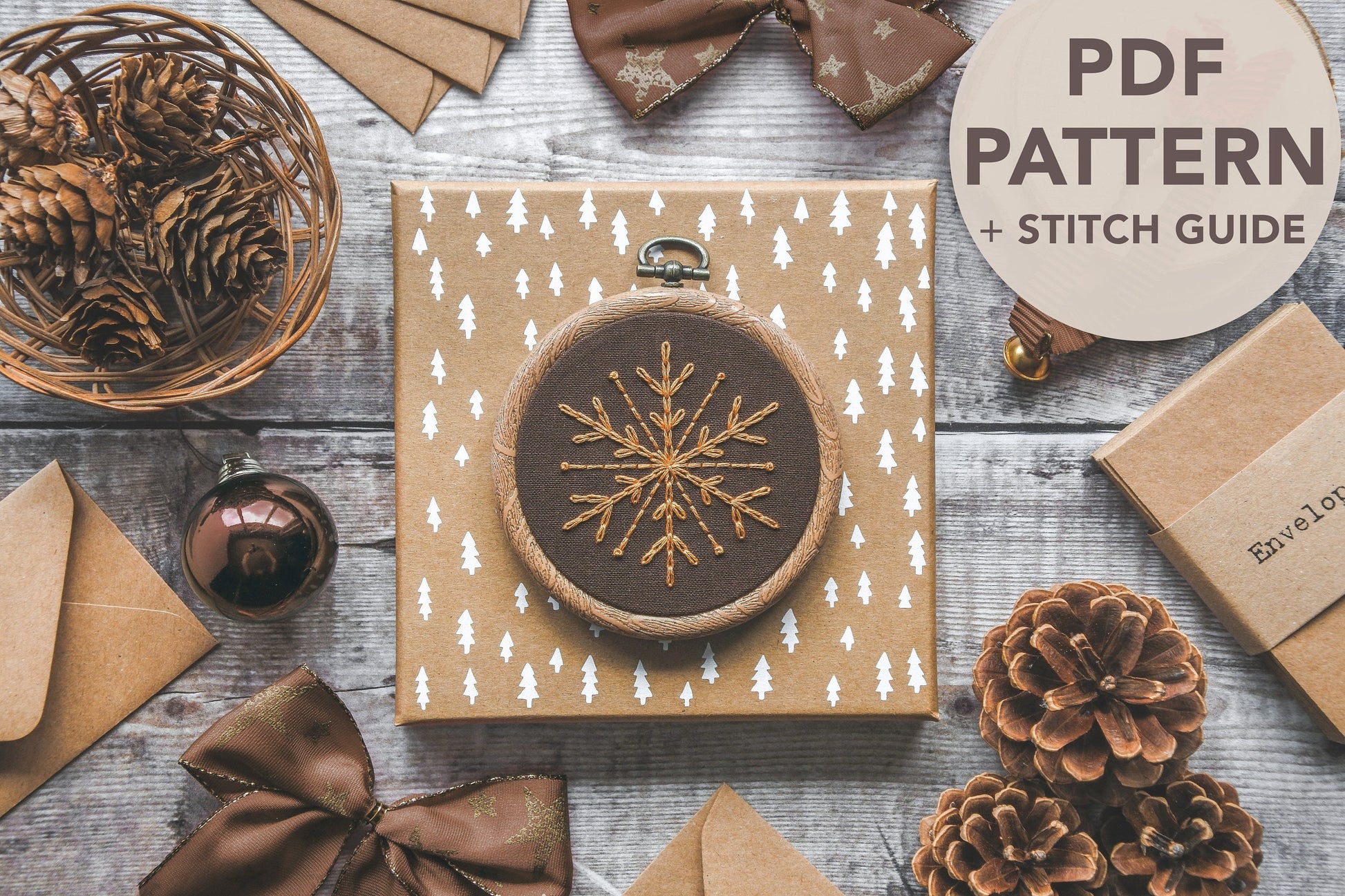 Flatlay of a gold snowflake embroidered on brown fabric, with overlaid text saying "PDF Pattern and Stitch Guide"