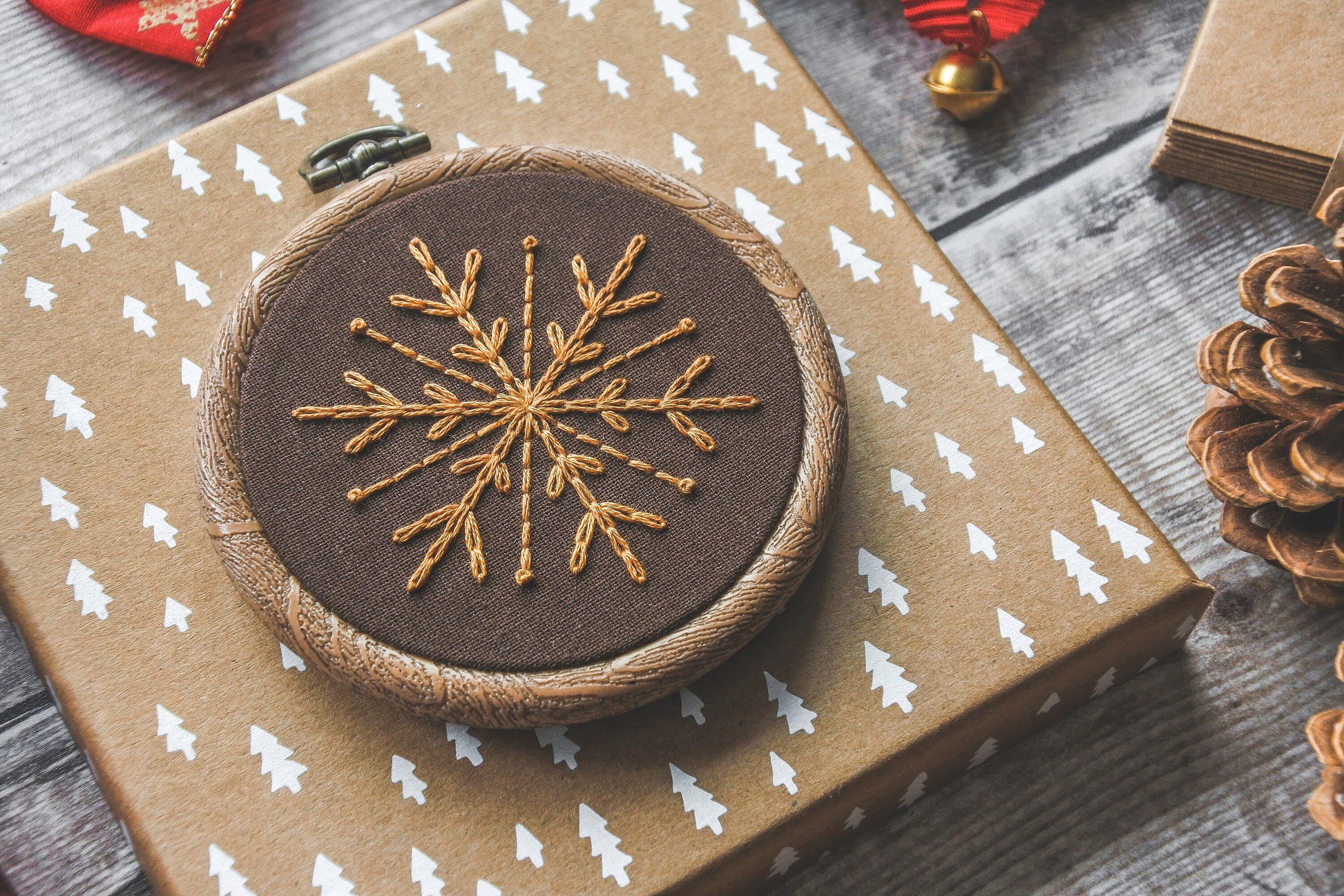 Gold snowflake embroidery on warm brown fabric in a 3-inch wood-effect hoop