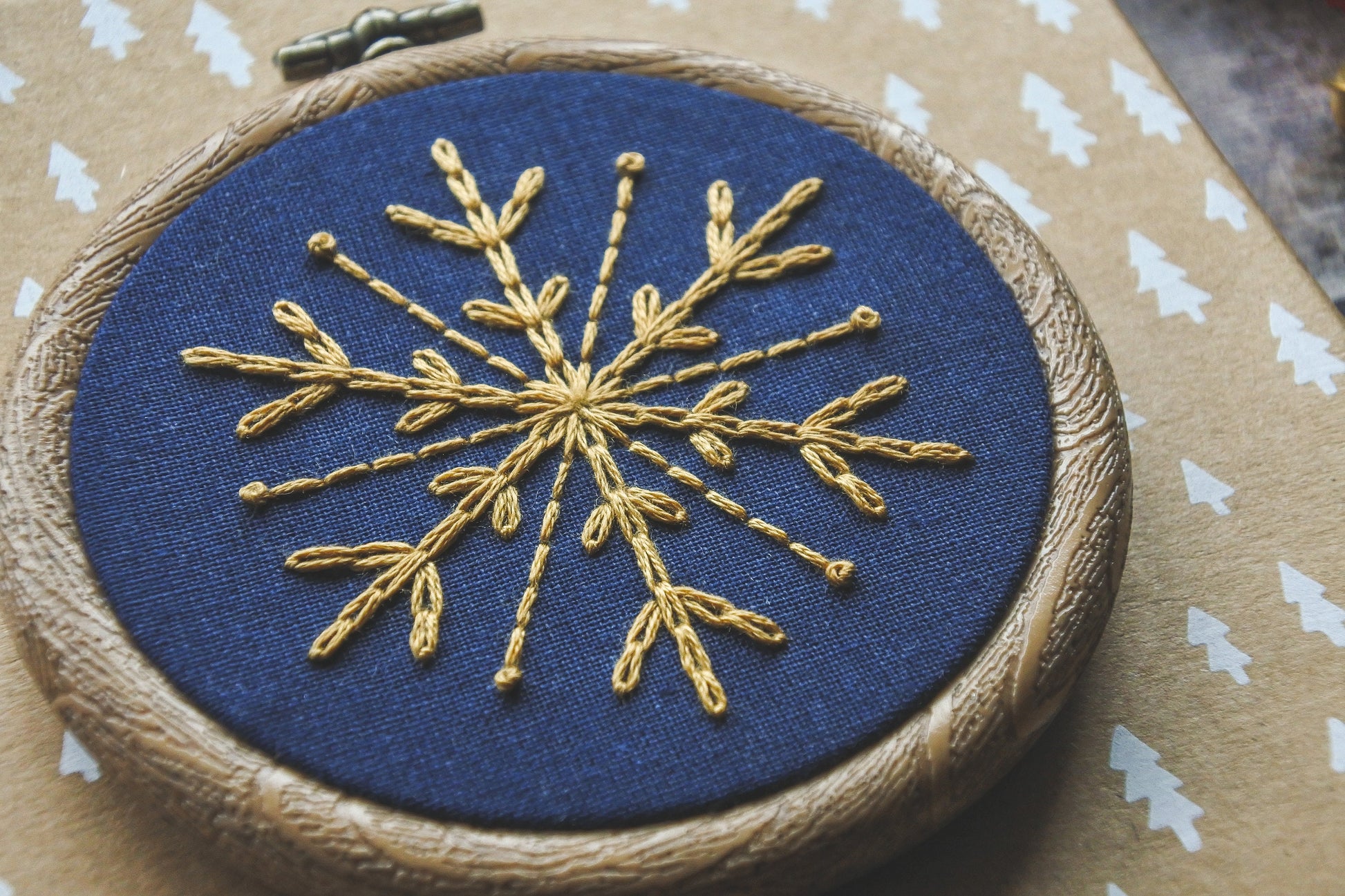 Finished gold snowflake on navy blue fabric in a 3-inch wood-effect hoop