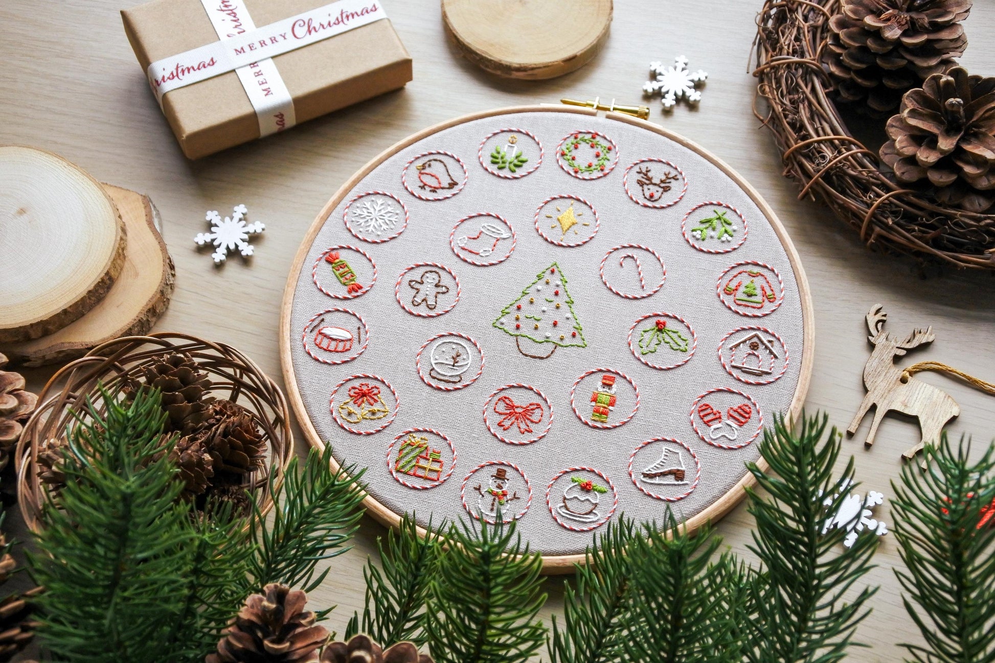 Flat lay of finished hand embroidered Christmas advent calendar hoop, featuring festive mini designs around a Christmas tree.
