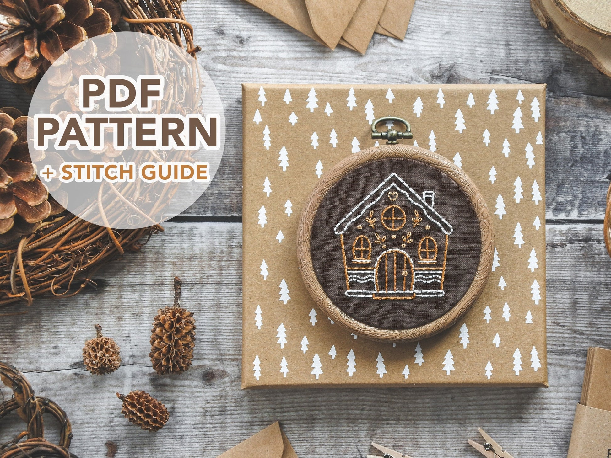 Hand-embroidered gingerbread house design on brown fabric, featuring leaf and heart icing accents. Includes text "PDF pattern and stitch guide."