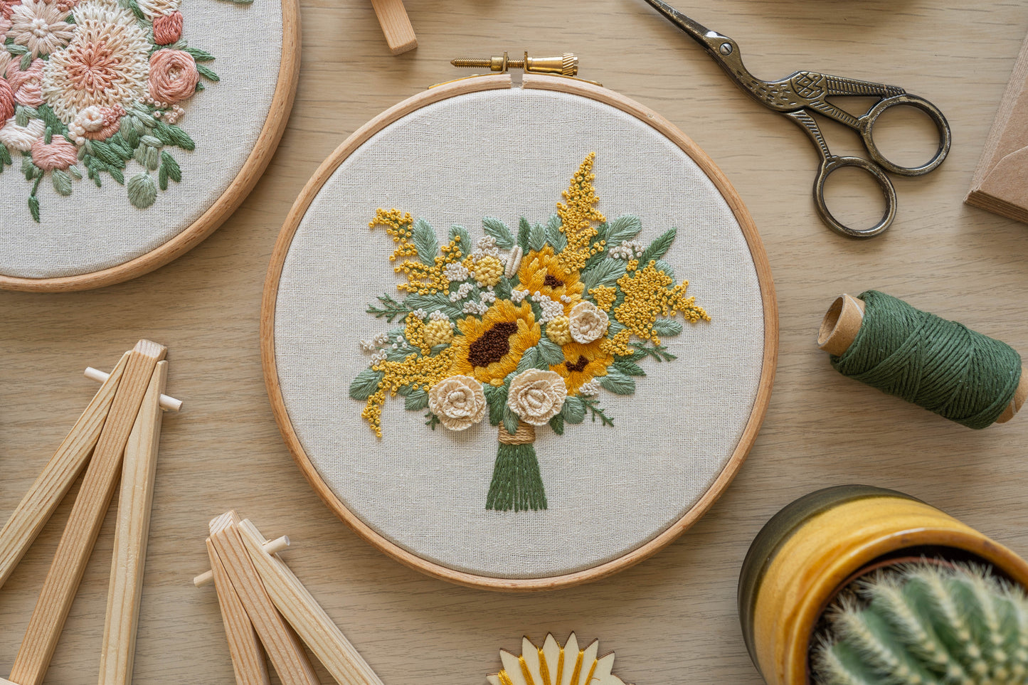 Custom hand-embroidered bouquet hoop with yellow, cream and white flowers featuring sunflowers, roses and eucalyptus leaves