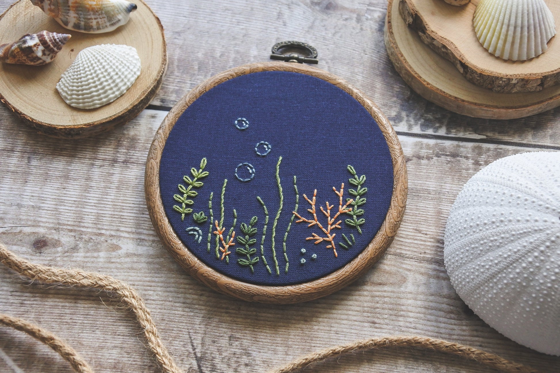 Hand-embroidered coral reef design in wood effect hoop on navy blue fabric
