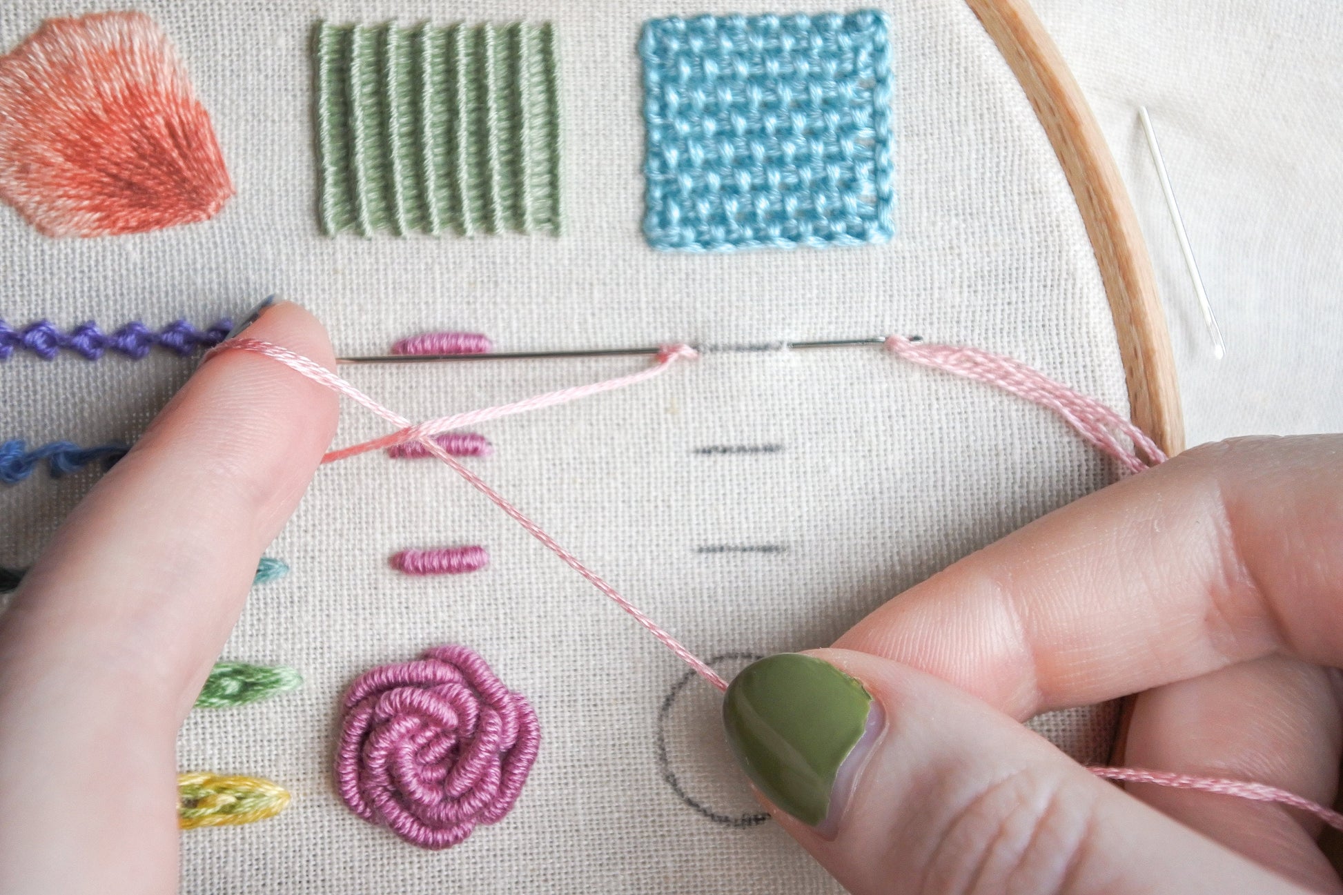 Hands looping light pink embroidery thread for cast-on stitch in progress on fabric