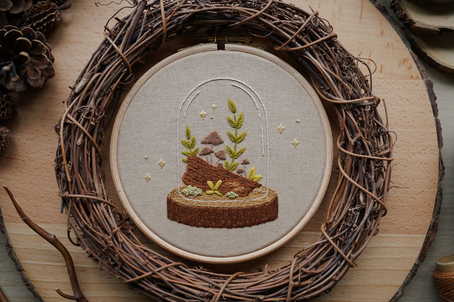 Embroidery hoop with nature-themed design on a wooden surface