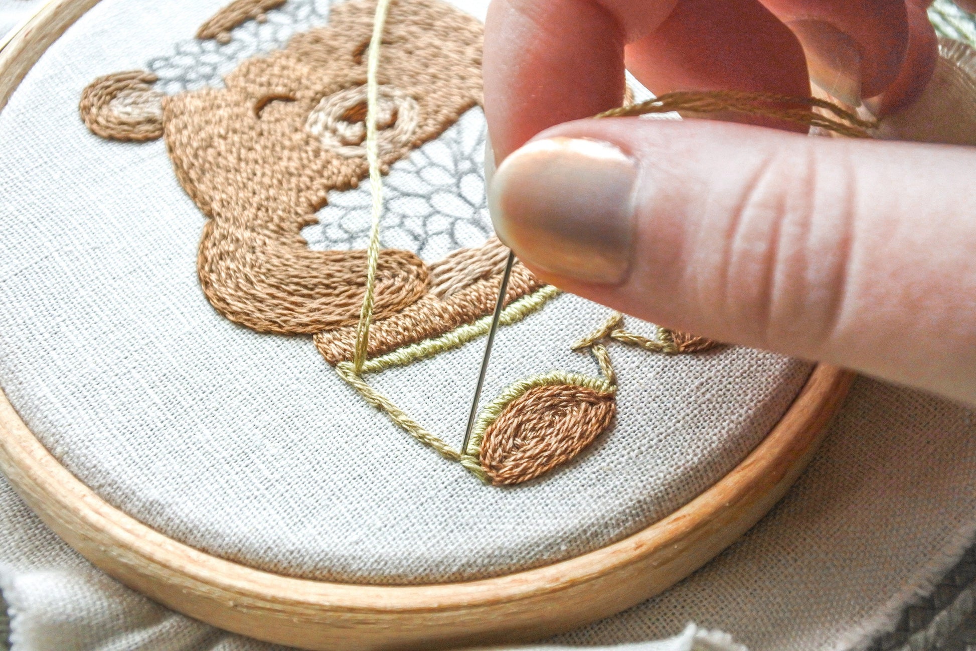 Close-up of stitching the bear’s green shorts in the embroidery design.