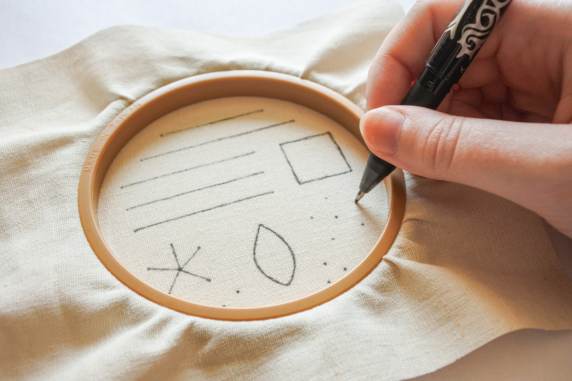 Hand using a heat erasable pen to transfer the embroidery pattern onto fabric
