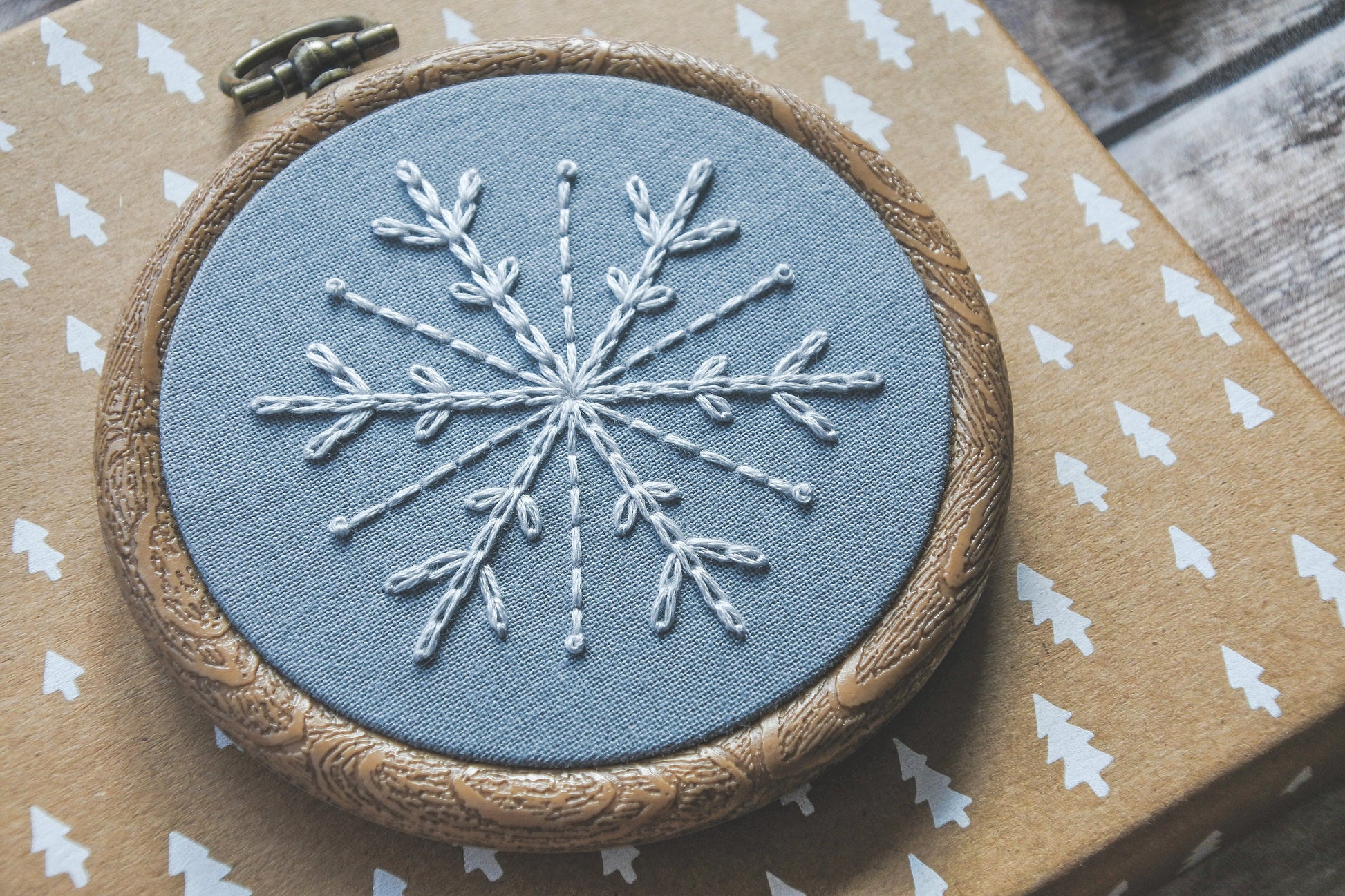 White snowflake on light blue fabric in a 3-inch wood-effect hoop